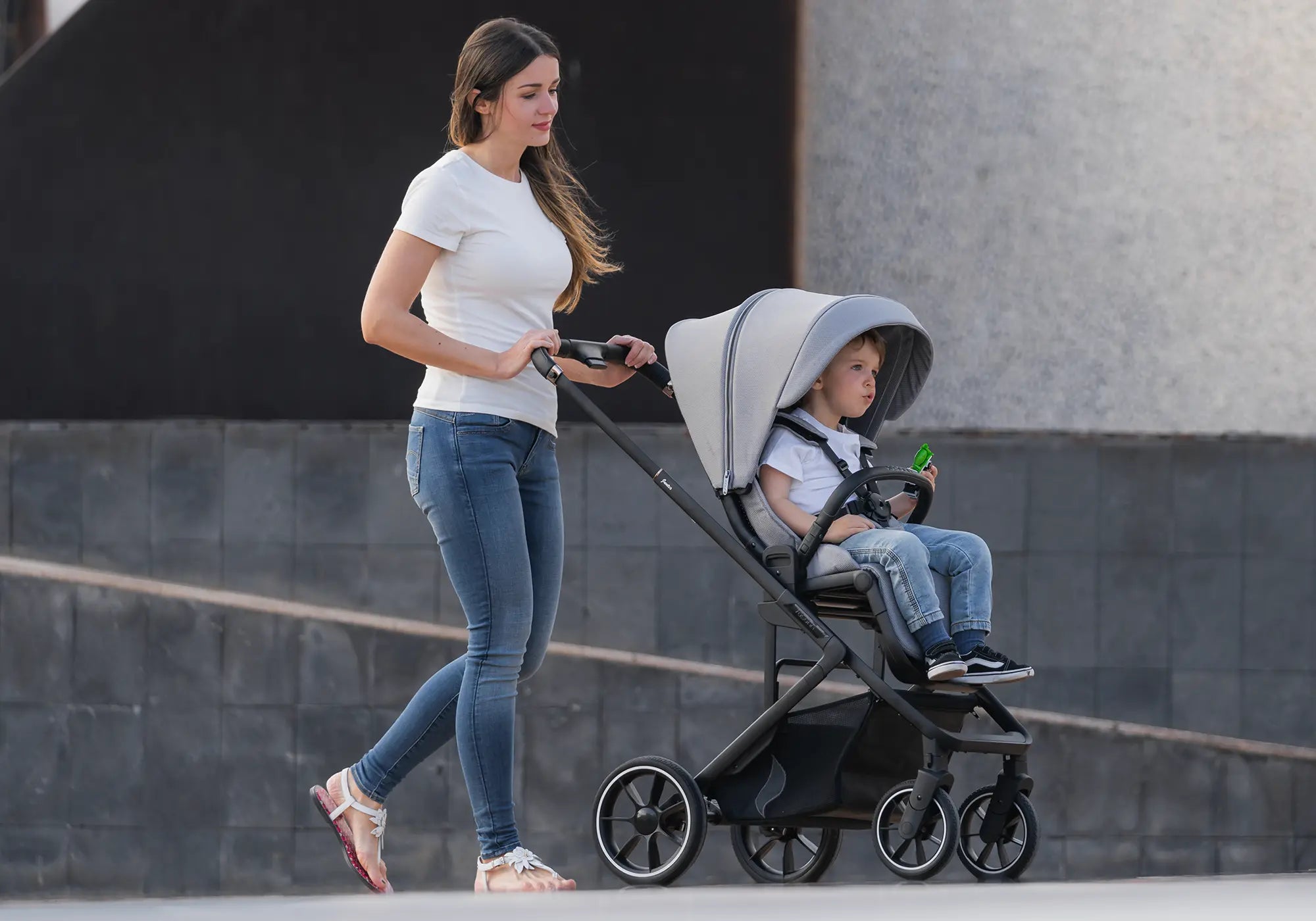 Mutter schiebt Kinderwagen Juntos mit Kind im Sportwagenaufsatz
