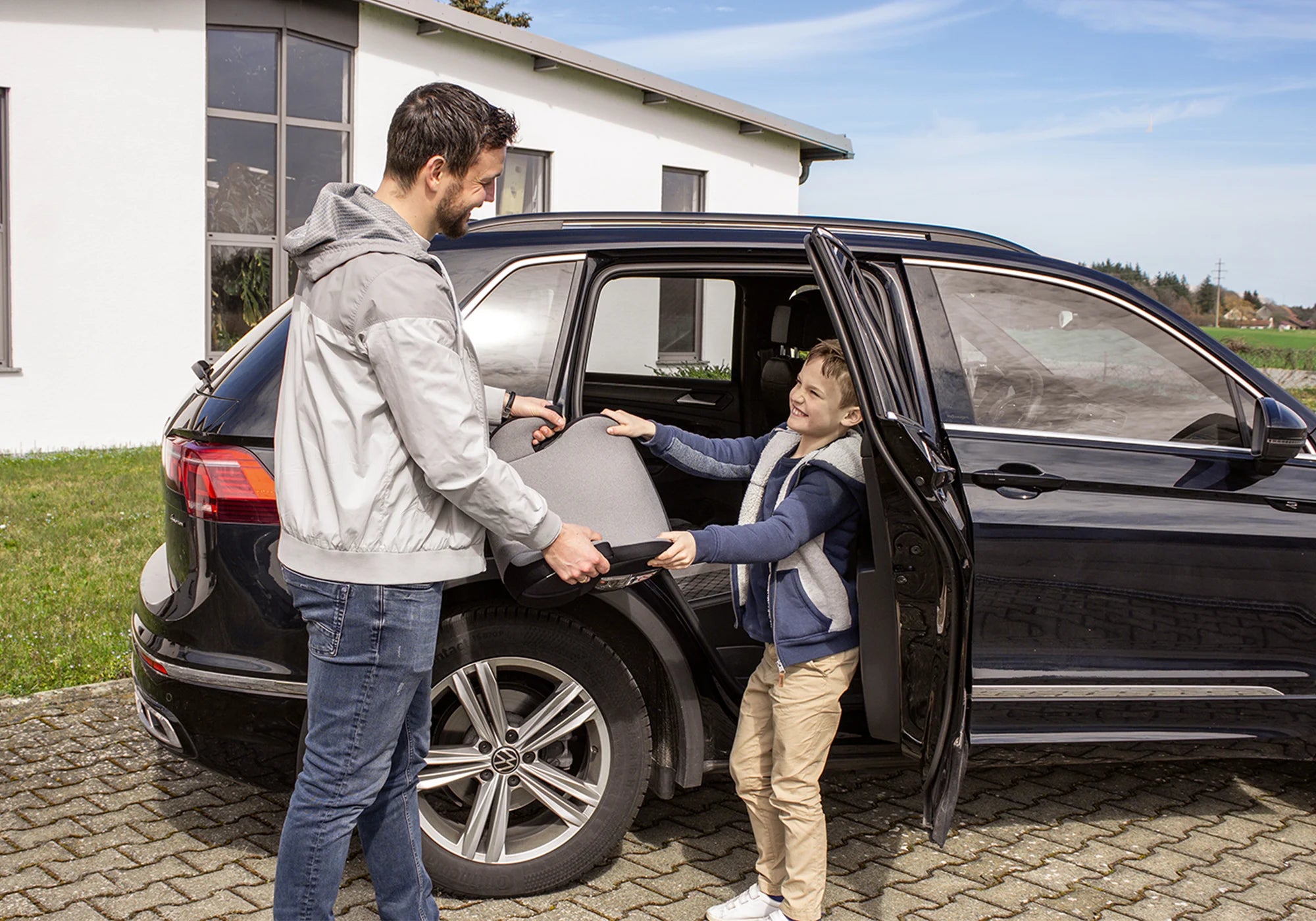 Vater und Sohn mit Booboo Sitzerhöhung vor Auto