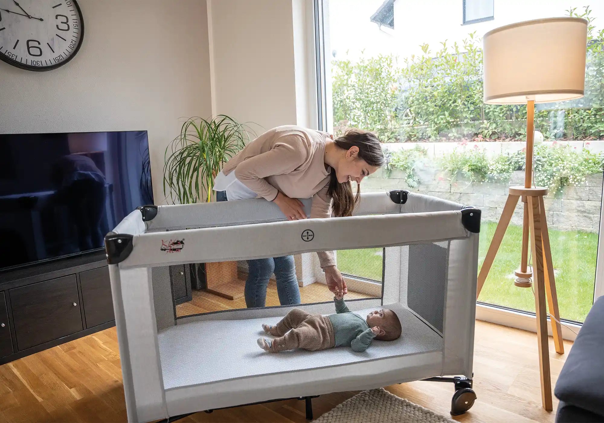 Mutter beugt sich zu Baby im Kids Alm Fresh Air Reisebett