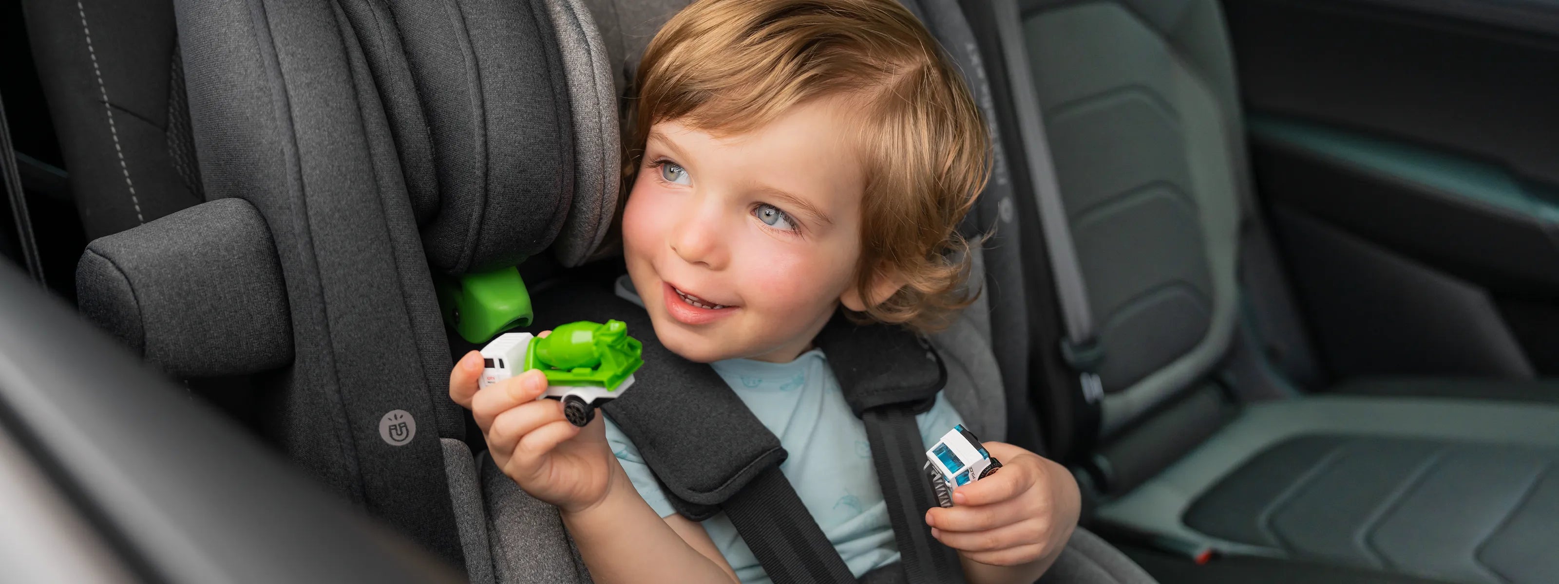 Kind mit Spielzeug im Kindersitz im Auto
