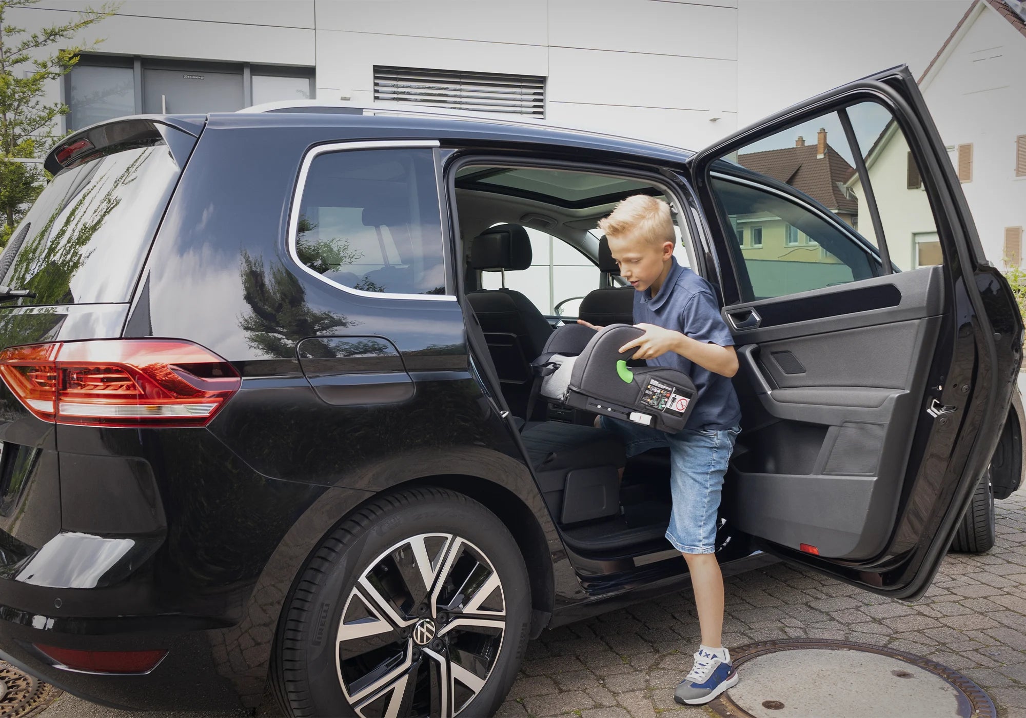 Junge mit Osann Sitzerhöhung Lux Isofix vor Auto